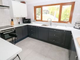 A kitchen with black cabinets white countertops a window over the sink and various appliances at Mill Barn Denant in Haverfordwest Pembrokeshire