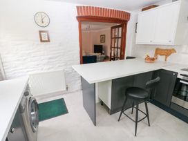 A kitchen with a white countertop bar stool washing machine and doorway leading to a living room at Mill Barn Denant in Haverfordwest Pembrokeshire