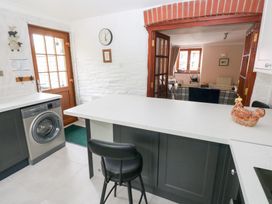 A kitchen with a washing machine black chair and a ceramic chicken on the counter at Mill Barn Denant in Haverfordwest Pembrokeshire