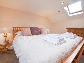 A bedroom with a wooden bed with pillows and folded towels a wooden dresser and bedside tables with lamps at Mill Barn Denant Haverfordwest Pembrokeshire