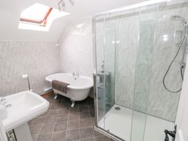 A bathroom with a clawfoot bathtub a glass-enclosed shower and a pedestal sink at Mill Barn Denant in Haverfordwest Pembrokeshire