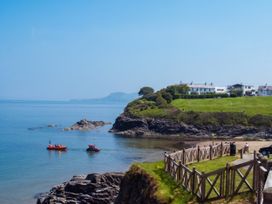 A view of the ocean with boats near a cliff and houses at Beach Retreat in Aberporth