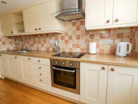 A kitchen with cabinets, a sink, and an oven at Beach Retreat, Aberporth
