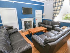 A living room with black leather sofas a wooden coffee table and a fireplace with a mounted TV at Newton West Farm in Newton near Newgale