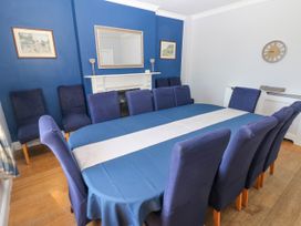 A dining room with a long table covered with a blue tablecloth and blue chairs around it at Newton West Farm Newton near Newgale
