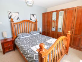 A bedroom with a wooden bed frame and matching wardrobes at Newton West Farm in Newton near Newgale