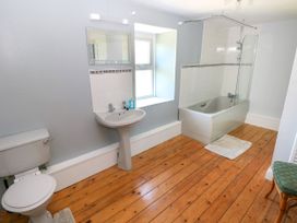 A bathroom with a toilet, sink, bathtub with shower, window, and wooden floor at Newton West Farm in Newton near Newgale