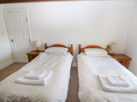 A bedroom with two single beds each with folded towels on top and wooden bedside tables with lamps Newton West Farm Newton near Newgale