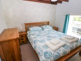 A bedroom with a wooden double bed with floral bedspread next to wooden bedside tables and a chest of drawers at Newton West Farm Newton near Newgale