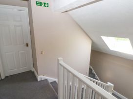 A stairway with white railing and a closed white door at the top with a fire exit sign on the wall at Newton West Farm Newton near Newgale