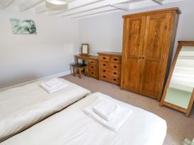 A bedroom with two single beds, wooden wardrobe, chest of drawers, dressing table with mirror, and standing mirror at Newton West Farm Newton near Newgale