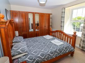 A bedroom with a wooden bed and large wooden wardrobes with mirrors at Newton West Farm Newton near Newgale
