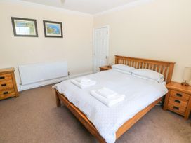 A bedroom with a wooden double bed with white bedding and towels on it two wooden bedside tables with lamps a wooden chest of drawers and two framed pictures on the wall at Newton West Farm in Newton near Newgale
