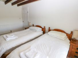 A bedroom with two single wooden beds each with white bedding and folded towels on top at Newton West Farm Newton near Newgale