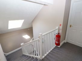 A staircase with white railing and a fire extinguisher mounted on the wall next to a closed door at Newton West Farm Newton near Newgale