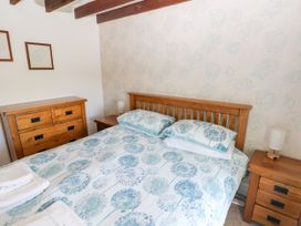A bedroom with a wooden double bed with floral bedding two wooden bedside tables with lamps and a wooden dresser at Newton West Farm Newton near Newgale