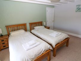 A bedroom with two single beds with wooden frames and white bedding at Newton West Farm Newton near Newgale