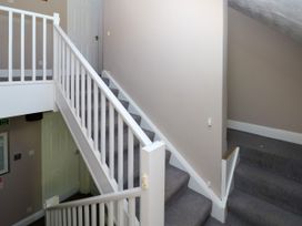 A staircase with white railings and grey carpet in a hallway at Newton West Farm in Newton near Newgale
