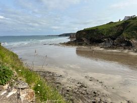 A beach with waves and a cliff at Beach Cottage in Little Haven, Pembrokeshire