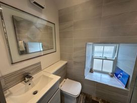 A bathroom with a sink, mirror, and toilet at Beach Cottage in Little Haven, Pembrokeshire