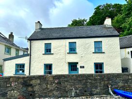 A house with blue windows and a sign at Beach Cottage in Little Haven, Pembrokeshire