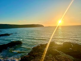 A sunset over the ocean with rocky shore at Beach Cottage in Little Haven, Pembrokeshire