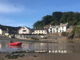 A beach scene with a red boat and houses at Beach Cottage in Little Haven, Pembrokeshire