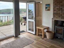 A living room with a table and a view at Beach Cove in Freshwater East, Pembrokeshire
