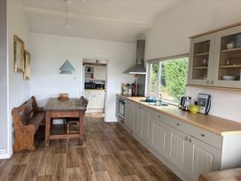 A kitchen with a table and benches at Beach Cove in Freshwater East, Pembrokeshire