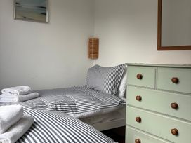 A bedroom with two beds and a dresser at Beach Cove, Freshwater East, Pembrokeshire