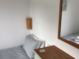 A bedroom with a bed, table, and lamp at Beach Cove, Freshwater East, Pembrokeshire