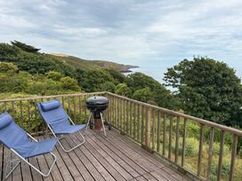 A deck with chairs and a barbecue at Beach Cove Freshwater East, Pembrokeshire