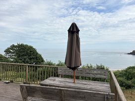 An outdoor seating area with a table and umbrella at Beach Cove, Freshwater East, Pembrokeshire