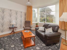 A living room with a sofa armchair coffee table and large windows at Coniston in Rhos Isaf