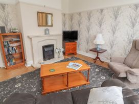 A living room with a fireplace a wooden coffee table armchair and television at Coniston in Rhos Isaf