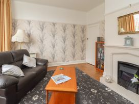 A living room with a leather sofa coffee table bookshelf fireplace and lamp at Coniston in Rhos Isaf