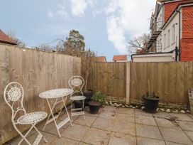 An outdoor patio area with a metal table and two chairs and several potted plants surrounded by wooden fences at Coniston in Rhos Isaf