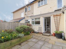 A small garden with plants and flowers patio and an open door leading to a dining area at Coniston in Rhos Isaf