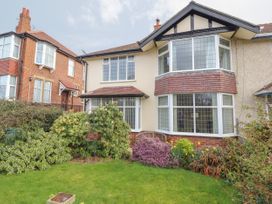 A front garden with bushes and flowers in front of a two story house with bay windows at Coniston in Rhos Isaf