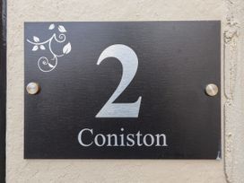 A black sign with the number 2 and text Coniston mounted on a beige wall at Coniston in Rhos Isaf