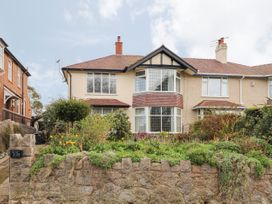 A semi detached house with a stone wall and garden in front at Coniston in Rhos Isaf