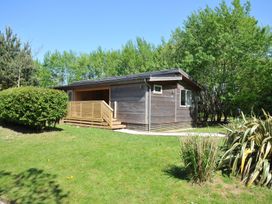 A wooden building with a deck in a grassy area at The Hideout in Lanreath