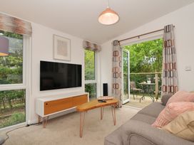 A living room with a television and access to an outdoor deck at The Hideout in Lanreath
