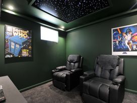 A home theater with recliner chairs and sci-fi posters at The Hideout in Lanreath
