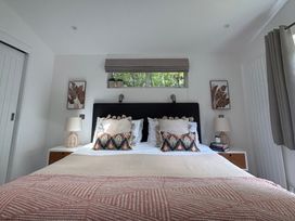 A bedroom with a bed and lamps on nightstands at The Hideout in Lanreath