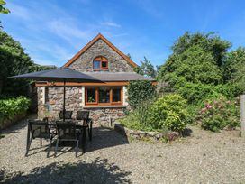 A house with a table and chairs under an umbrella at Barn Court Cottage Narberth, Pembrokeshire