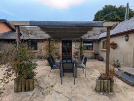 A dining area with a table and chairs under a pergola at Stoney Cottage in Narberth, Pembrokeshire