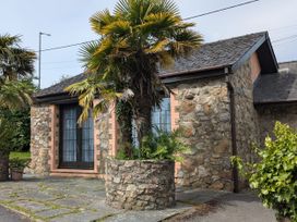 A stone exterior with palm trees and a planter at Stoney Cottage in Narberth, Pembrokeshire