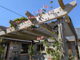 A pergola with flowers and a building at Stoney Cottage in Narberth, Pembrokeshire