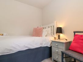 A bedroom with a bed, nightstand, lamp, and chair at Weavers Cottage, Carlton-in-Cleveland near Stokesley